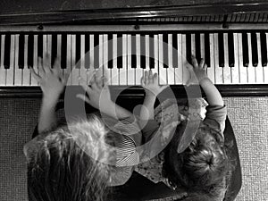 Two children play music on piano