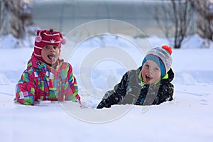 Two children play in the snow on a winter day