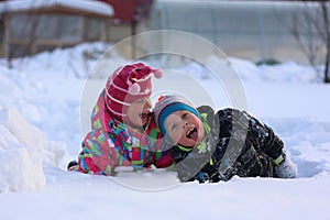 Two children play in the snow on a winter day. Children play in a snowdrift. Cheerful children on a winter frosty day in the park