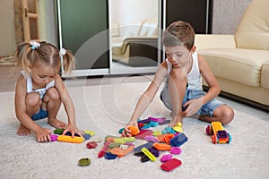 Two children playing with blocks on the floor at home