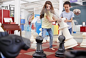 Two children playing giant chess at a science centre