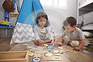 Two Children Playing Number Puzzle Game Together In Playroom