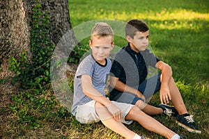 Two children are playing in the park. Two beautiful boys in T-shirts and shorts have fun smiling. They eat ice cream