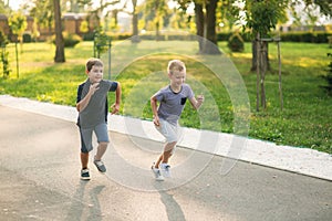 Two children are playing in the park. Two beautiful boys in T-shirts and shorts have fun smiling. They eat ice cream