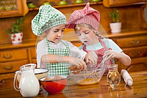 Two children preparing eggs for cookies in the kitchen