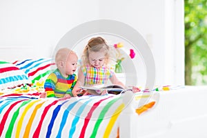 Two children reading a book in bed