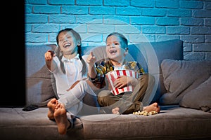 two children with remote control watching TV
