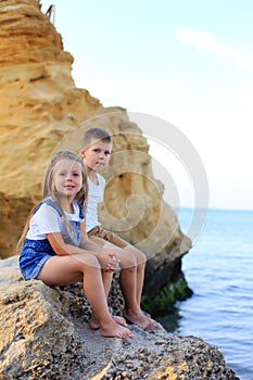 Two children are on the rocks by the sea