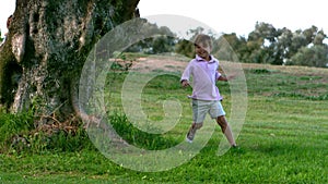 Two children running around a tree playing chasing