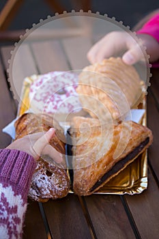 Two children`s hands take fresh sweet pastries.