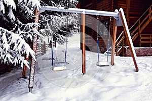 Two children`s swings covered with snow