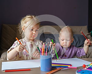Two children sister and baby boy brother drawing with pencils together at home