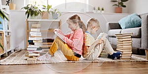 Two children sitting on the floor in the room and reading books