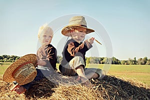 Two Children Sitting on Hay Bale in Autumn