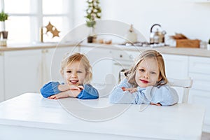 Two children sitting on the kitchen table.