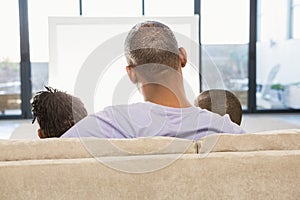 Two children sitting on sofa with their father