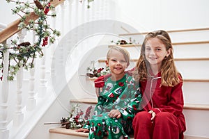 Two Children Sitting On Stairs In Pajamas At Christmas