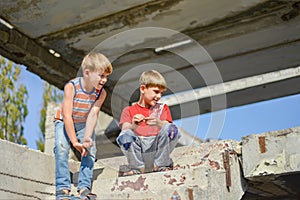 Two children are sitting on the steps of an abandoned building, a concept of the life of street children orphans