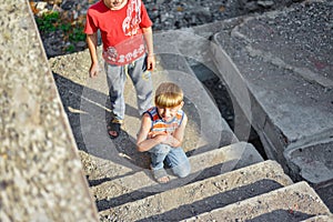 Two children are sitting on the steps of an abandoned building, a concept of the life of street children orphans