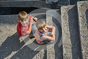 Two children are sitting on the steps of an abandoned building, a concept of the life of street children orphans