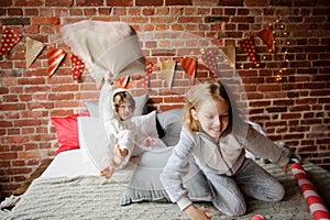 Two children in soft pyjamas have arranged fight by pillows.