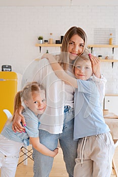 Two children son and daughter hug their mother. Happy loving family standing