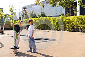 Two children spining on carousel and laughing loudly, hanging out, having fun in playground. happy activities