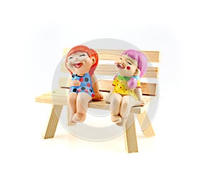 Two children statue to happy and smile , sitting on the wooden c