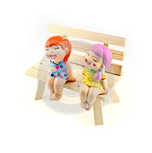 Two children statue to happy and smile , sitting on the wooden c