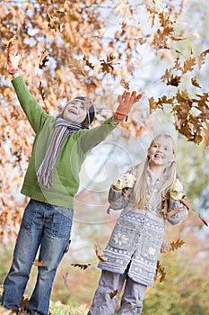 Two children throwing leaves in the air