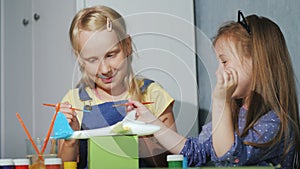 Two children together paint a model of a somet with watercolors. Lessons for the development of children`s options