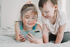 Two children are watching a cartoon on the phone. Children`s addiction to gadgets. Two sisters communicate on the Internet