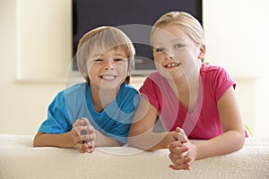 Two Children Watching Widescreen TV At Home