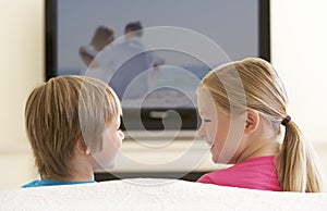 Two Children Watching Widescreen TV At Home