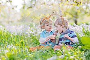 Two children wearing Easter bunny ears and eating chocolate