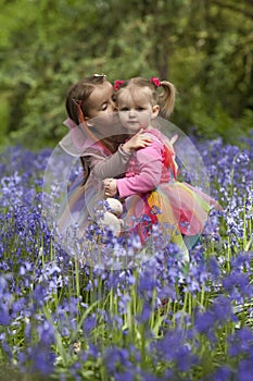 Two children in a wood filled with spring bluebells