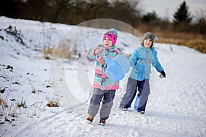 Two children of younger school age spend time in winter day with pleasure.