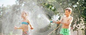 Two childs playing in garden, pours each other from the hose, makes a rain. Happy childhood concept image