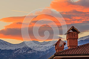 Two chimneys of a house on the background of a sunset