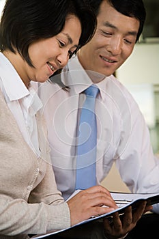 Two Chinese businesspeople reading a document