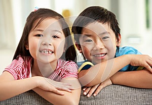 Two Chinese Children Relaxing On Sofa At Home