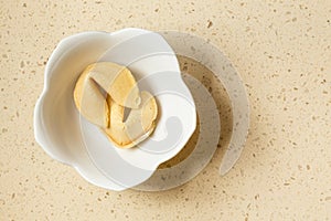 Two Chinese fortune cookies in a white bone china bowl sitting on a quartz countertop