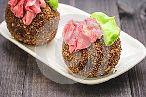 two chocolate cakes in a white plate on a wooden background/two chocolate cakes in a white plate on a wooden background. selective