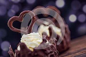 Two chocolate desserts filled with white cream on wooden table, dessert with chocolate hearts for valentines or wedding day