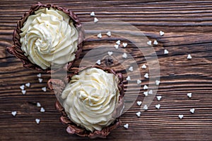 Two chocolate desserts filled with white cream on wooden table, dessert with white hearts for valentines day