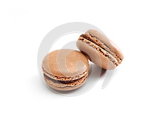 Two chocolate macaroons on white surface.