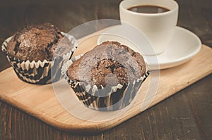 Two chocolate muffins and cup coffee on a wooden tray/two chocolate muffins and cup coffee on a wooden tray and dark table