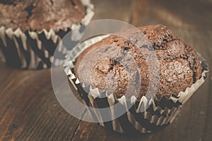 two chocolate muffins/two chocolate muffins on a dark wooden table. Close up