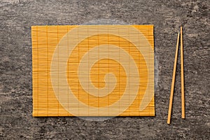 Two chopsticks and bamboo mat on cement background. Top view, copy space