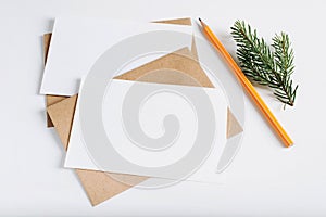 Two Christmas blank greeting cards mock-up. Craft envelopes, pine twig, pencil and card template with empty space for text